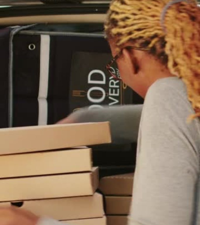 垂直视频: 非裔美国女快递员拿走了一大堆披萨盒
