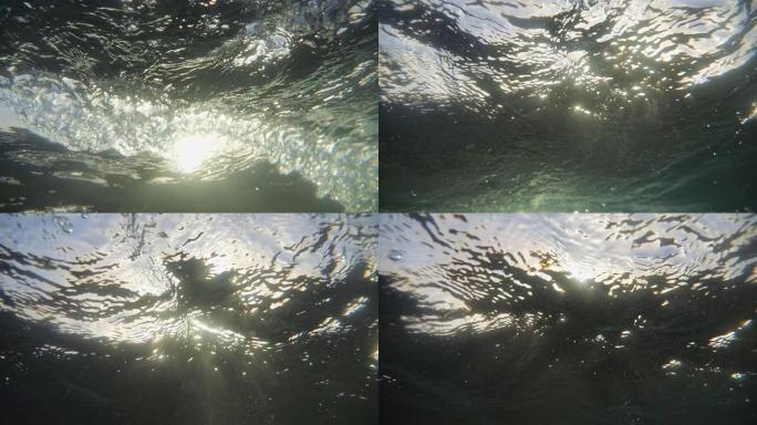 水面下的海浪。太阳、天空和水面从水面下面。靠近水面和水深的气泡，被天空和太阳光线背光。版本7