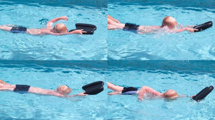 游泳教练教一个孩子游泳。夏天，白人儿童戴着泳镜在游泳池里学习游泳。慢动作