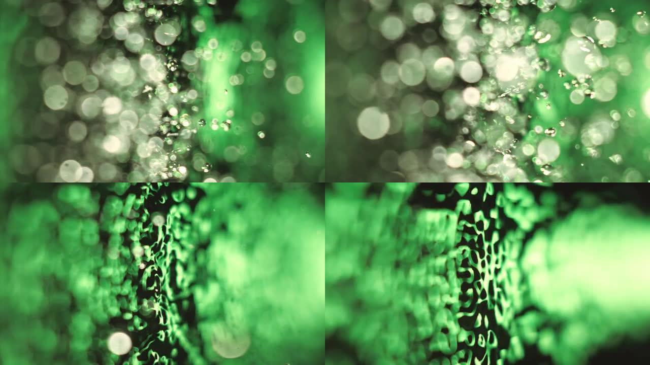 绿色霓虹灯照亮的飞溅水的超慢动作。振动下降分离并反弹成单独的元素。表面张力。