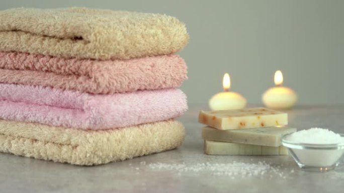 相机在用肥皂和燃烧的蜡烛堆叠的棉质毛圈毛巾上移动