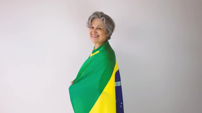 穿着黄色衬衫和巴西国旗的足球高级女球迷庆祝白色孤立的杯赛