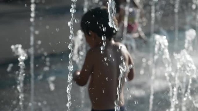 暑假期间，孩子在城市公园的喷水中行走