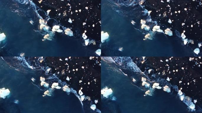 带有光反射的纯净蓝色海水波浪在冰岛的火山海滩上粉碎了冰山