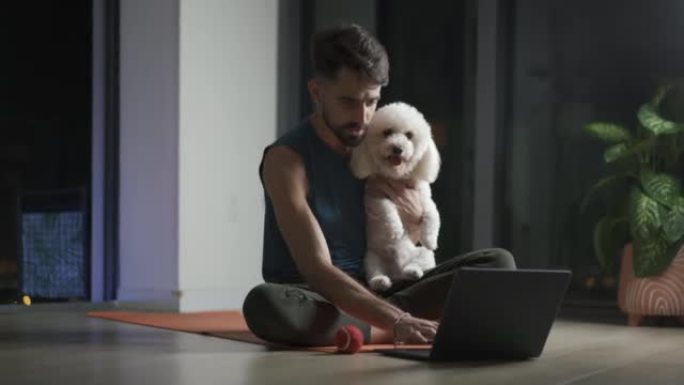 年轻的拉丁男子在锻炼时休息一下，和他的狗一起玩