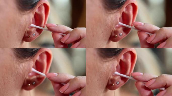 一名妇女用棉签清洁耳朵，动作缓慢