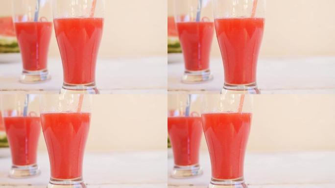 两个高高的玻璃玻璃杯，上面装有可重复使用的玻璃管，里面装有红色西瓜饮料架，放在白色桌子上特写镜头，多