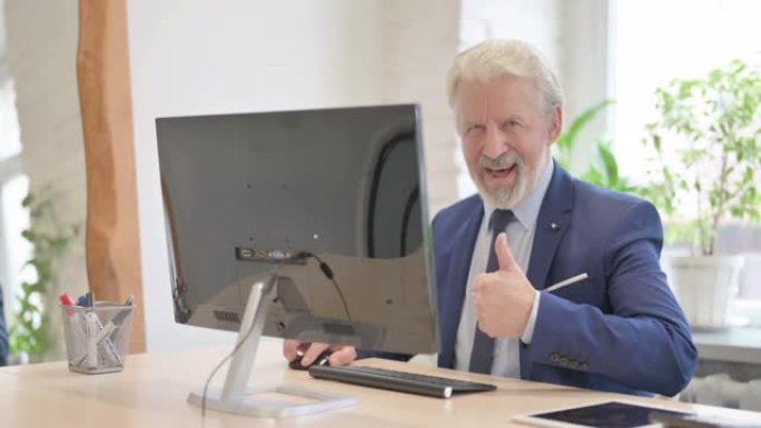 资深老商人在使用台式电脑时竖起大拇指