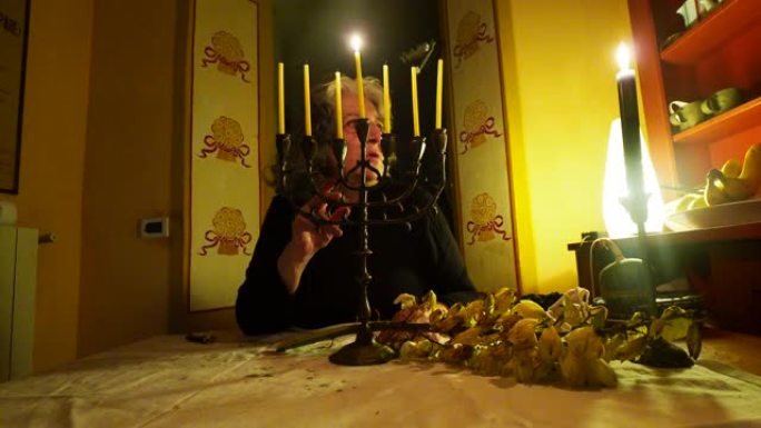 一名妇女坐在烛光下的桌子旁庆祝犹太节日Hannukah的镜头