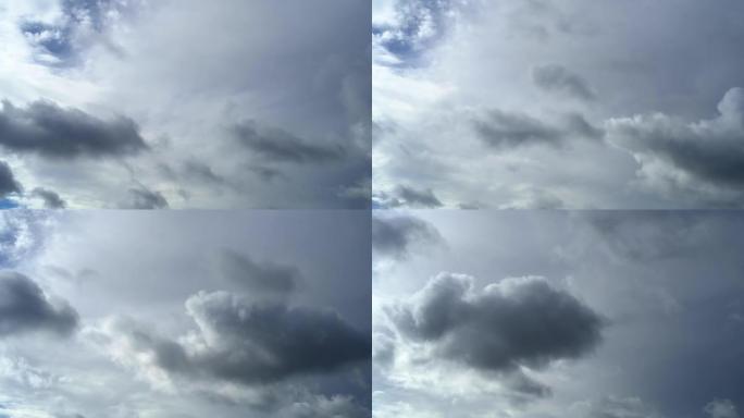 小小的灰色雨云在大白云的背景下横穿天空。