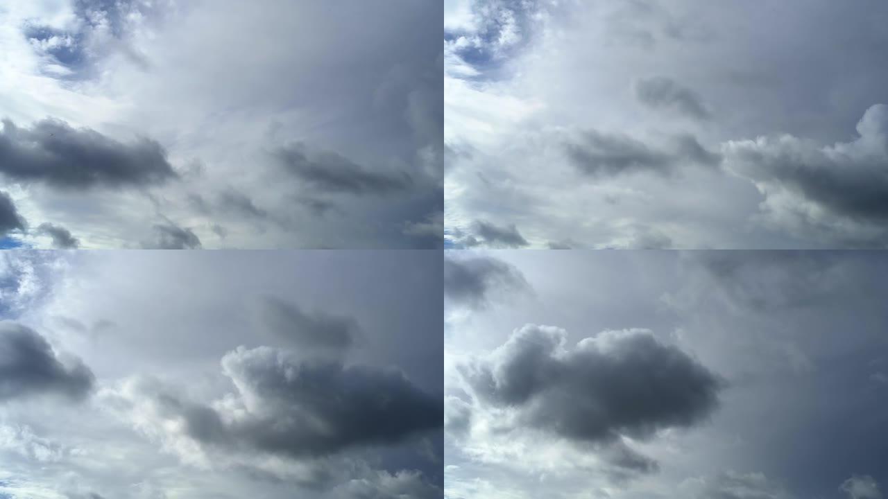 小小的灰色雨云在大白云的背景下横穿天空。