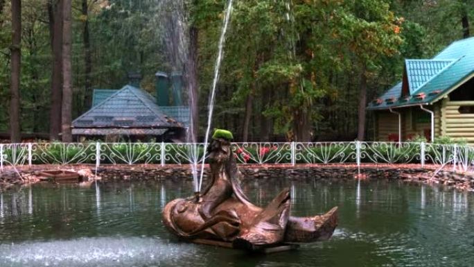 池塘中央的装饰喷泉。木结构: 美人鱼坐在岩石上。