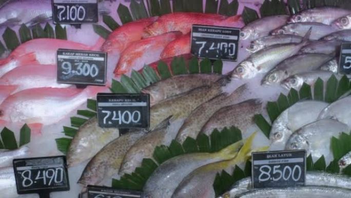 海洋附近市场上的摊位上有很多新鲜的海鲜鱼，有冰和绿叶，价格标签。从当地水库在超市出售鱼，以养鱼