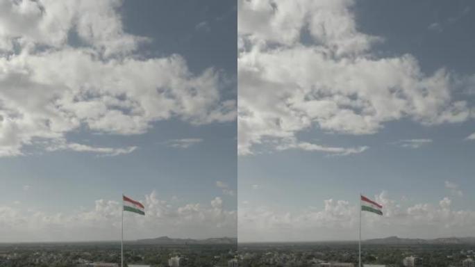 在干燥的田野上城市中心挥舞着印度国旗的鸟瞰图