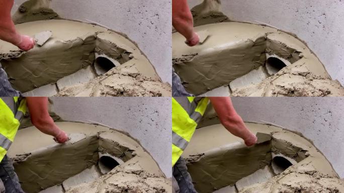 建造者在钻孔并在其中形成通道的同时，用抹子将沙子和水泥与抹子混合并平整