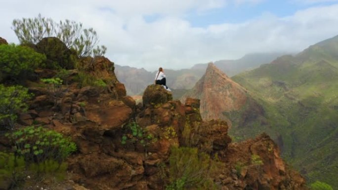 日出时山顶上女人的剪影。空中飞行。惊人的悬崖。西班牙特内里费加那利岛。旅游目的地。去任何地方。独自坐