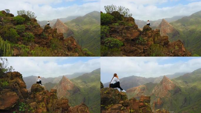 日出时山顶上女人的剪影。空中飞行。惊人的悬崖。西班牙特内里费加那利岛。旅游目的地。去任何地方。独自坐