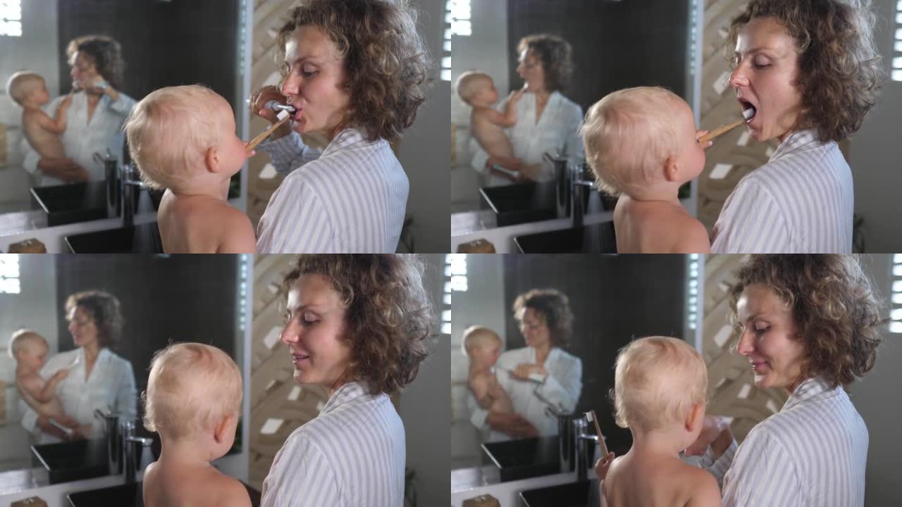 年轻的高加索母亲抱着婴儿一起刷牙。他们每天都有自己的晨练。他们一起刷牙很开心。