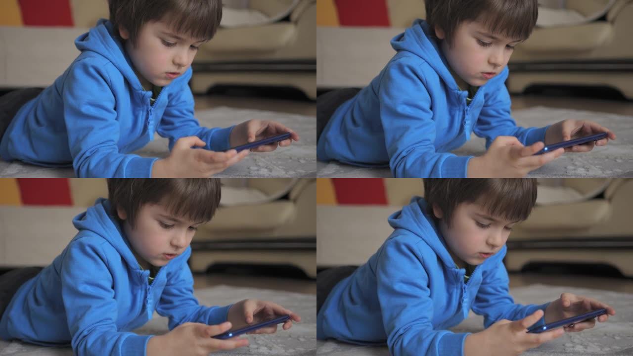 孩子躺在家里的电话里玩游戏。孩子在手机上玩电子游戏。男孩玩电子游戏智能手机。儿童使用手机进行游戏在线