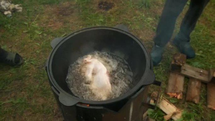 男人正在用黑卡赞的鸡肉和沸腾的油煎炸。