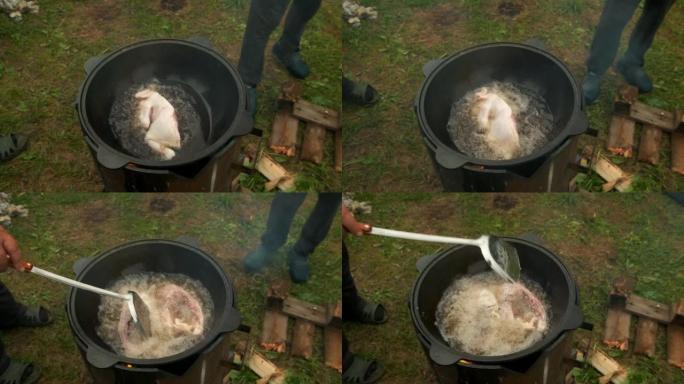 男人正在用黑卡赞的鸡肉和沸腾的油煎炸。