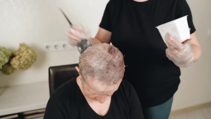 一个女女儿用刷子画她年迈的母亲的头发。