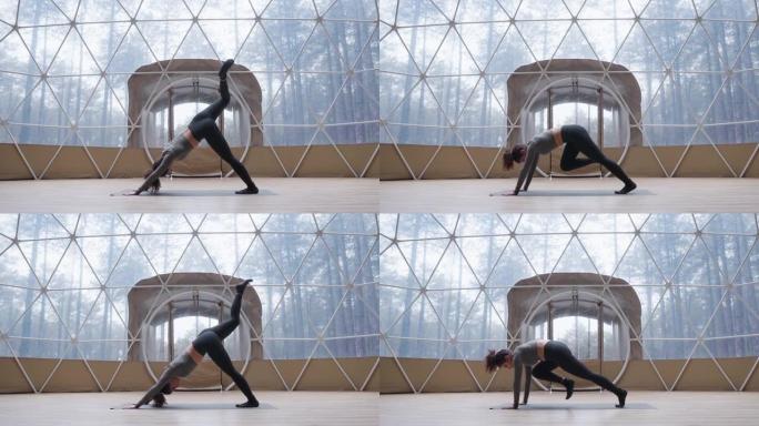 卷发混血女孩练习瑜伽，在概念圆顶工作室做体式。年轻女子穿着黑色灰色运动服站在垫子上练习瑜伽。健身的概