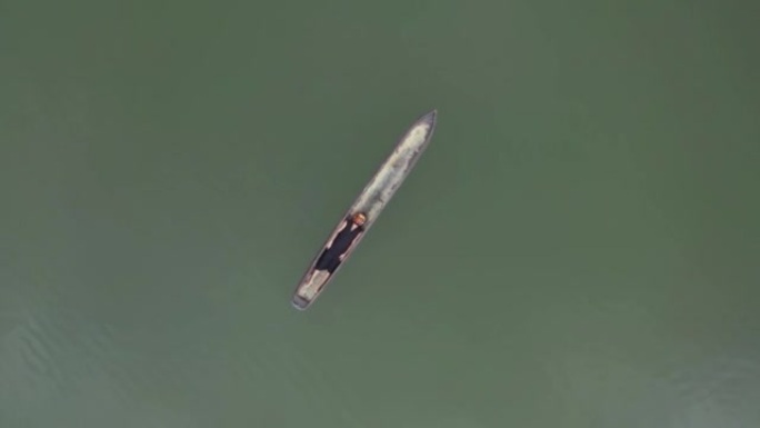 戴着面具躺在独木舟漂浮在水面上的萨满的鸟瞰图。实时