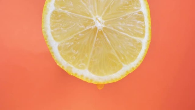 柠檬汁从果肉中流出，并在橙色背景上滴落，宏观视频，文字运动