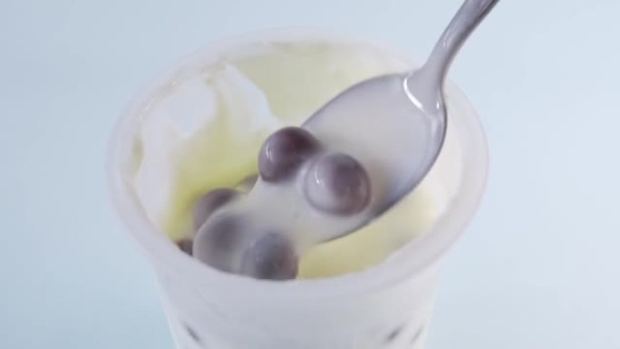 用勺子将酸奶和一些巧克力球混合在塑料杯中
