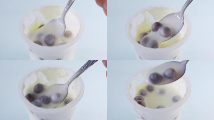 用勺子将酸奶和一些巧克力球混合在塑料杯中