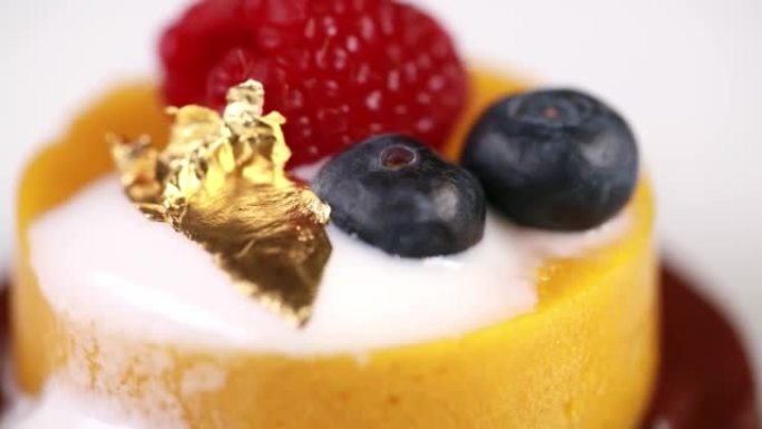 用蓝莓，覆盆子和金片装饰的新鲜美味芒果慕斯的特写镜头