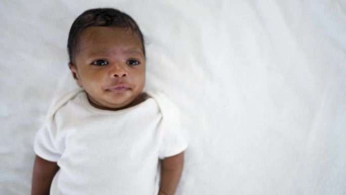 非洲快乐宝宝躺在床上的特写肖像，白色背景上有复制空间。健康的新生儿睡个午觉。家庭爱新生儿保健医疗理念