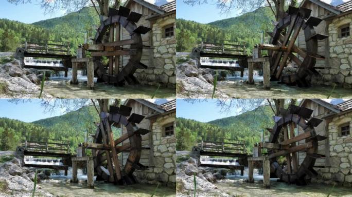 旧的木制水磨，背景是一个小瀑布和石头房子。斯洛文尼亚的丘陵和木材丰富多彩的背景。4k 50 fps镜