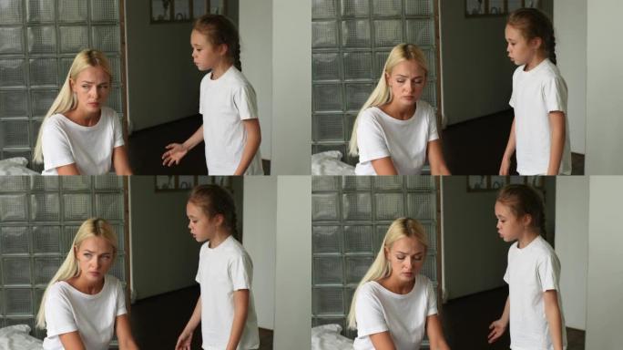站在愤怒的小孩女儿的肖像责骂，提高声音，尖叫着悲伤的年轻母亲坐在家里的沙发上。