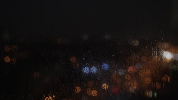 晚上雨滴从窗户上跑下来。模糊的，五彩的光闪烁。