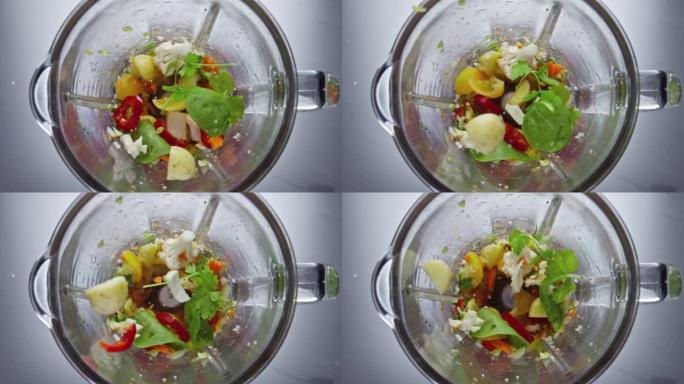 搅拌机刀片以超慢动作切割蔬菜。特写蔬菜混合