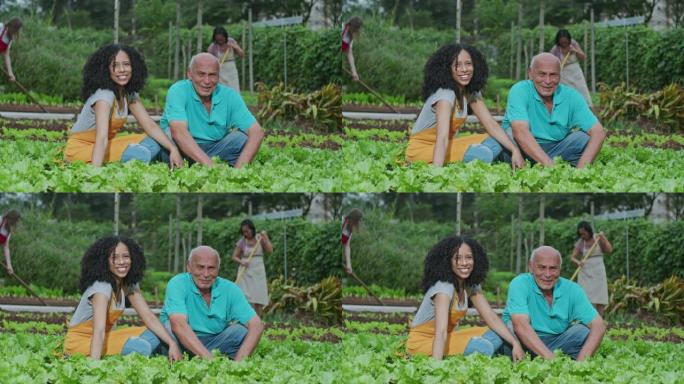 两个不同的人在户外耕种的肖像对着镜头微笑，背景工人使用耕种工具耕种有机食品。快乐的南美社区园丁