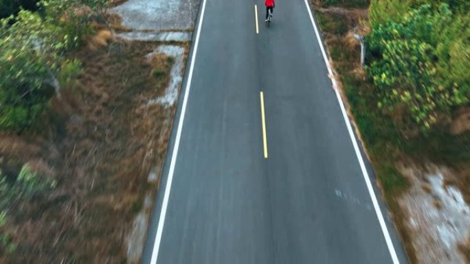 骑自行车公路旅行与女运动员骑手在早上的无人机视图