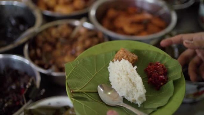 来自井里汶的典型烹饪Nasi Jamblang最喜欢的村民。服务员正在将豆豉，炸虾放在柚木叶盘上加米