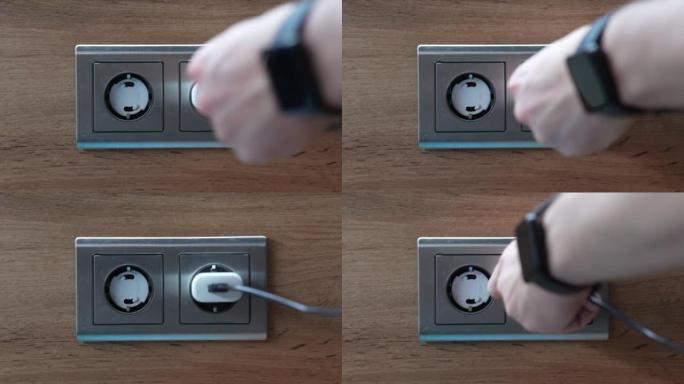 男子插拔壁式充电器。将充电器适配器手动插入墙壁插座。