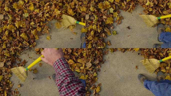 人从水泥人行道上扫落秋叶。