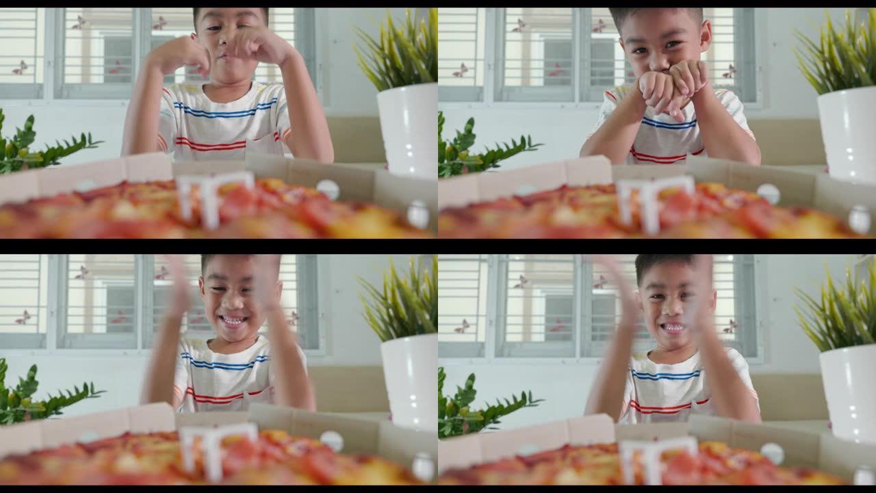 快乐的亚洲小男孩5年打开披萨纸板，在家里的桌子上非常惊讶和快乐