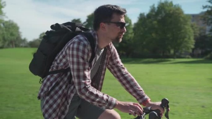 骑自行车的人在自行车的车把上使用智能手机进行导航。男性骑自行车的人在德国的公园骑自行车，并使用GPS