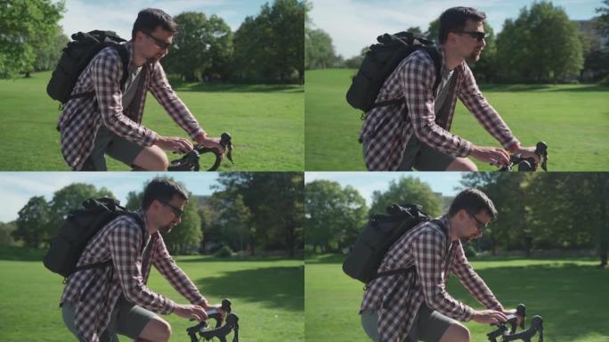 骑自行车的人在自行车的车把上使用智能手机进行导航。男性骑自行车的人在德国的公园骑自行车，并使用GPS