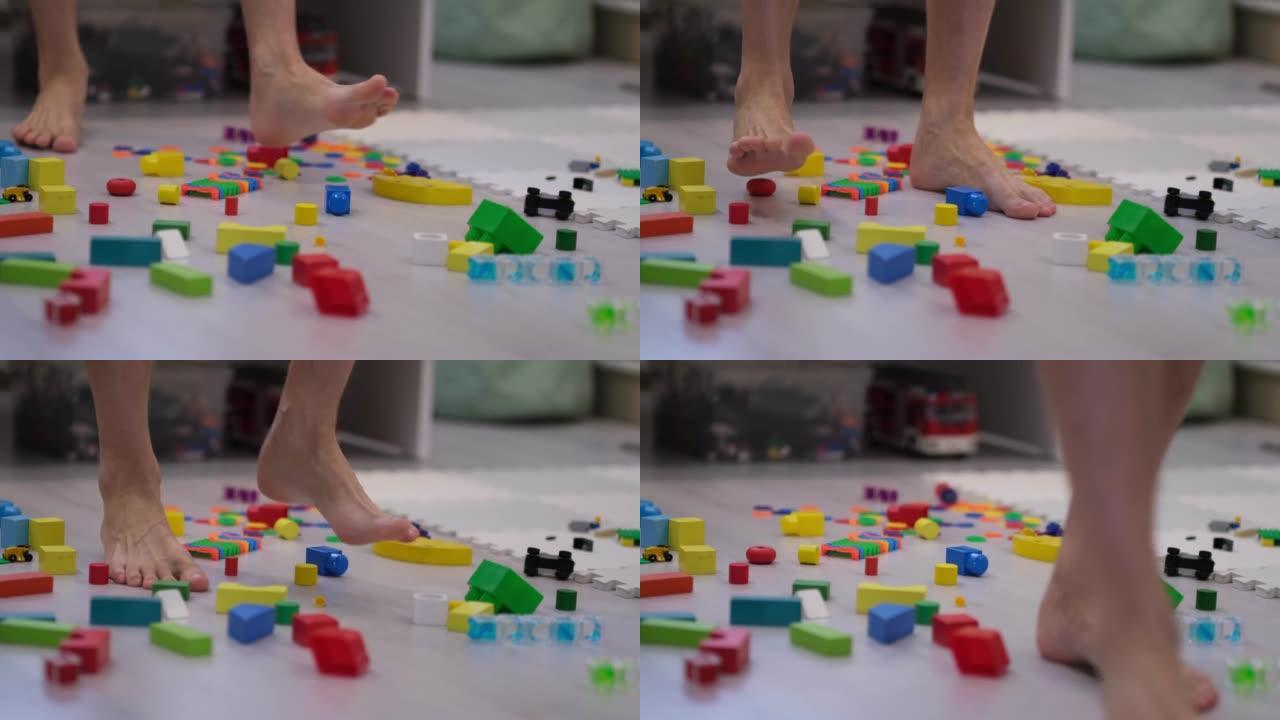 赤脚的人走在零散的玩具之间。脚踩在儿童玩具上。散落在地板上的玩具。现代世界中大量玩具的概念。