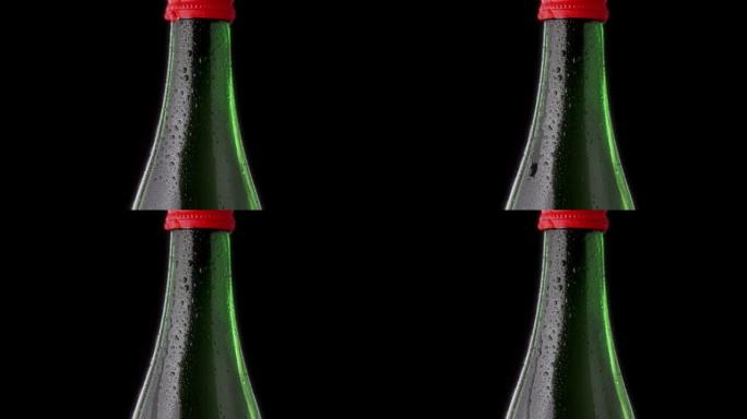 一滴从瓶子里掉下来。绿色一瓶红色瓶盖的矿泉水。水滴玻璃瓶