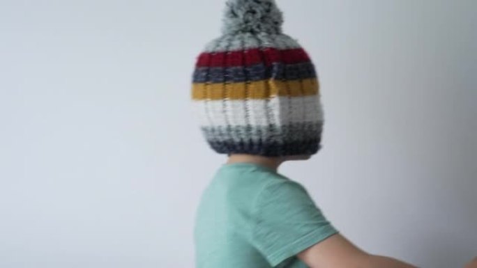 孩子的脸覆盖着豆豆帽。有趣的顽皮小男孩盲针织羊毛冬季配件