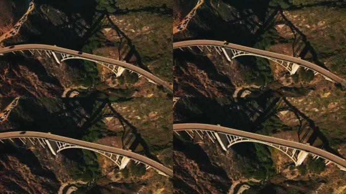桥上的路越过山脉之间的缝隙。晴天降落在美丽的桥梁建筑之上。从顶部看。