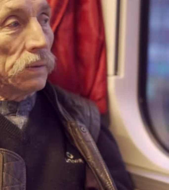 垂直视频-戴眼镜的老人在火车上旅行，看着窗外，早上与他的良心交谈